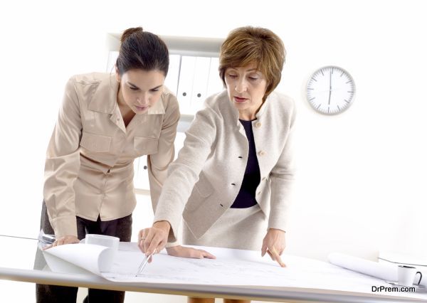 Female architects designing on blueprint at office.