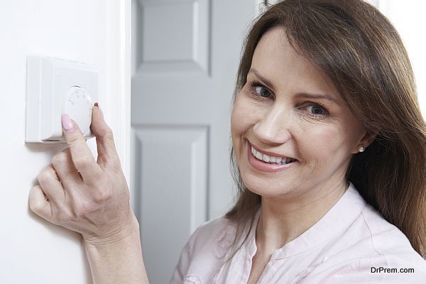 Woman Adjusting Thermostat On Central Heating Control