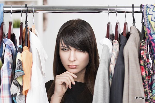 Beautiful young woman near rack with clothesc