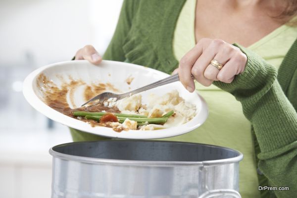 Woman Scraping Food Leftovers Into Garbage Bin