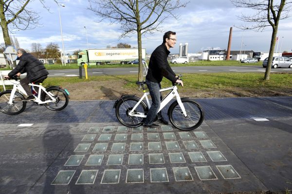 Cyclists use the SolaRoad, the first road in the world made of solar panels, during the official opening in Krommenie on November 12, 2014. The Netherlands unveiled the world's first solar bike path, a revolutionary project to harvest the sun's energy that could eventually also be used on roads. The so-called "SolaRoad" bike path is made of concrete modules each measuring 2.5 by 3.5 metres (eight by 11 feet), embedded with solar panels covered in tempered glass. AFP PHOTO/ANP/EVERT ELZINGA == NETHERLANDS OUT == (Photo credit should read EVERT ELZINGA/AFP/Getty Images)