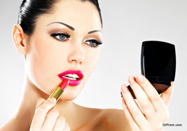 Beautiful woman applying pink lipstick on lips