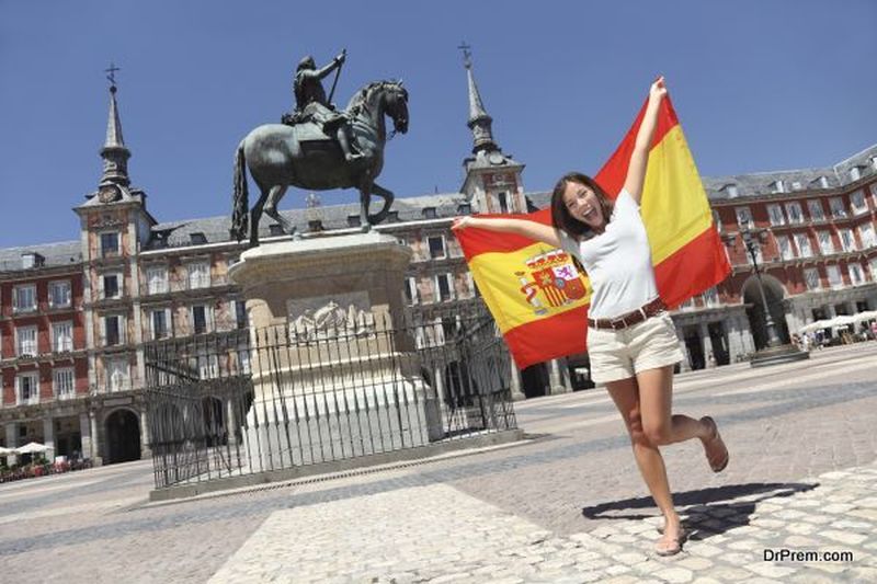 Madrid woman tourist on Plaza Mayor screaming with Spain flag.